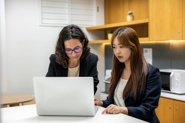 Duas Mulheres Sentadas Em Uma Mesa Olhando Para Um Laptop 6TahDwED_ws