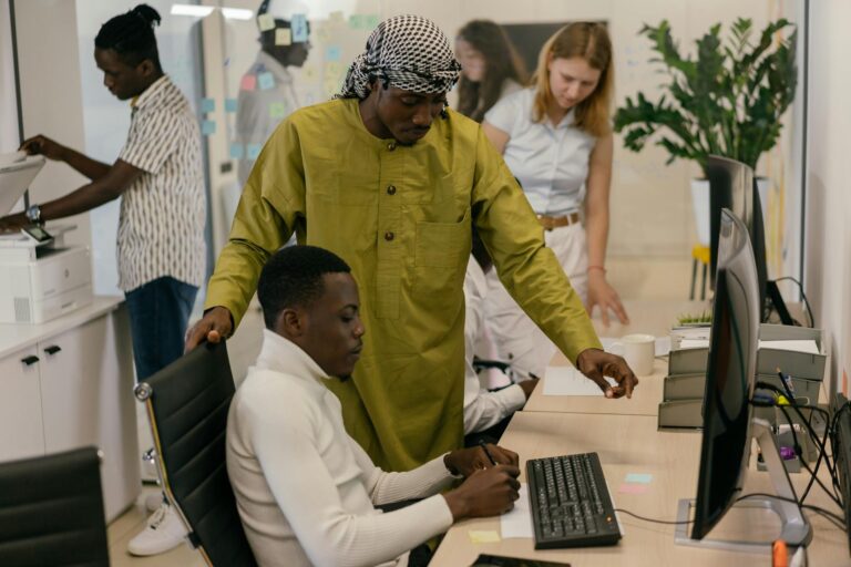 Multicultural team working collaboratively in a modern office setting with computers and documents.