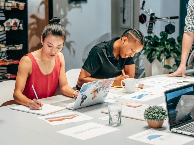 A diverse team engaged in a collaborative office meeting, analyzing data and taking notes.