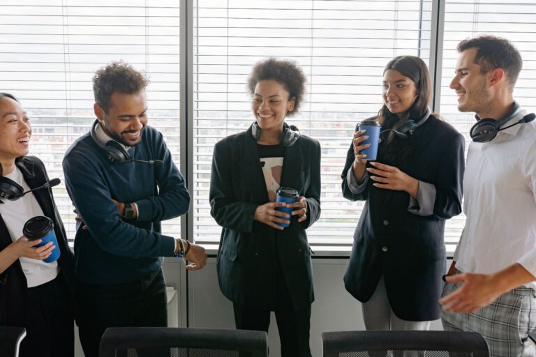 A diverse group of call center agents enjoying a casual break in the office, sharing laughs and hot drinks.