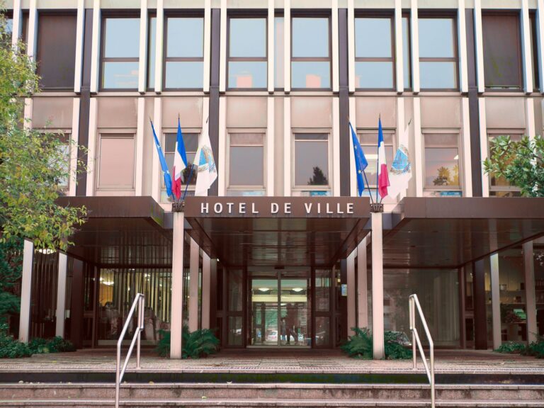 Front view of Hotel de Ville in Vélizy-Villacoublay, France with flags and modern architecture.
