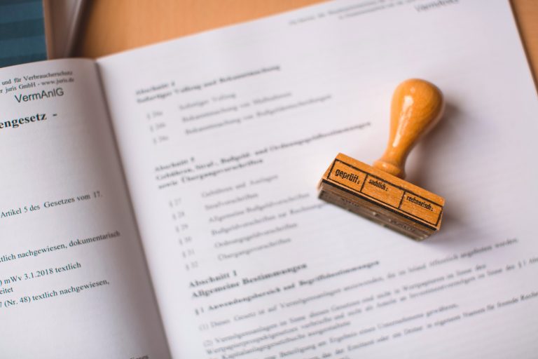 A wooden rubber stamp resting on an open German legal document